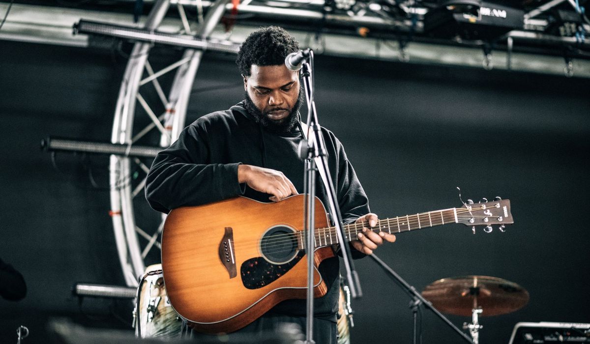 Musician with an acoustic electric guitar at a microphone on stage