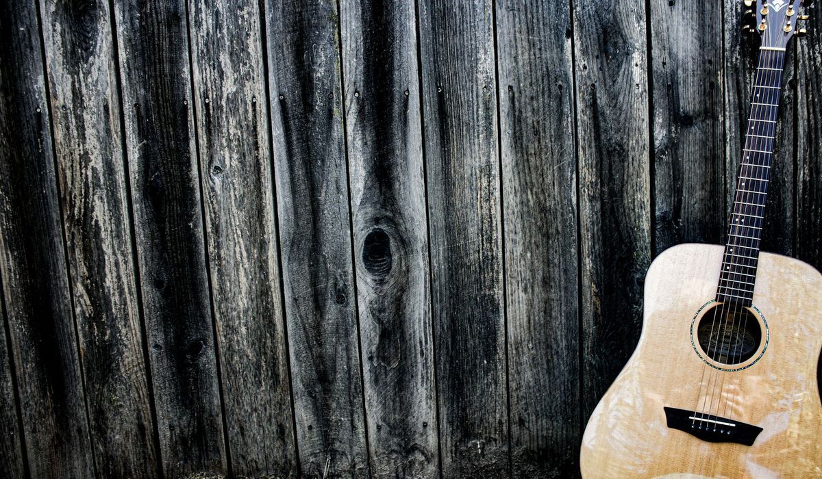 Acoustic guitar leaning against a wooden wall