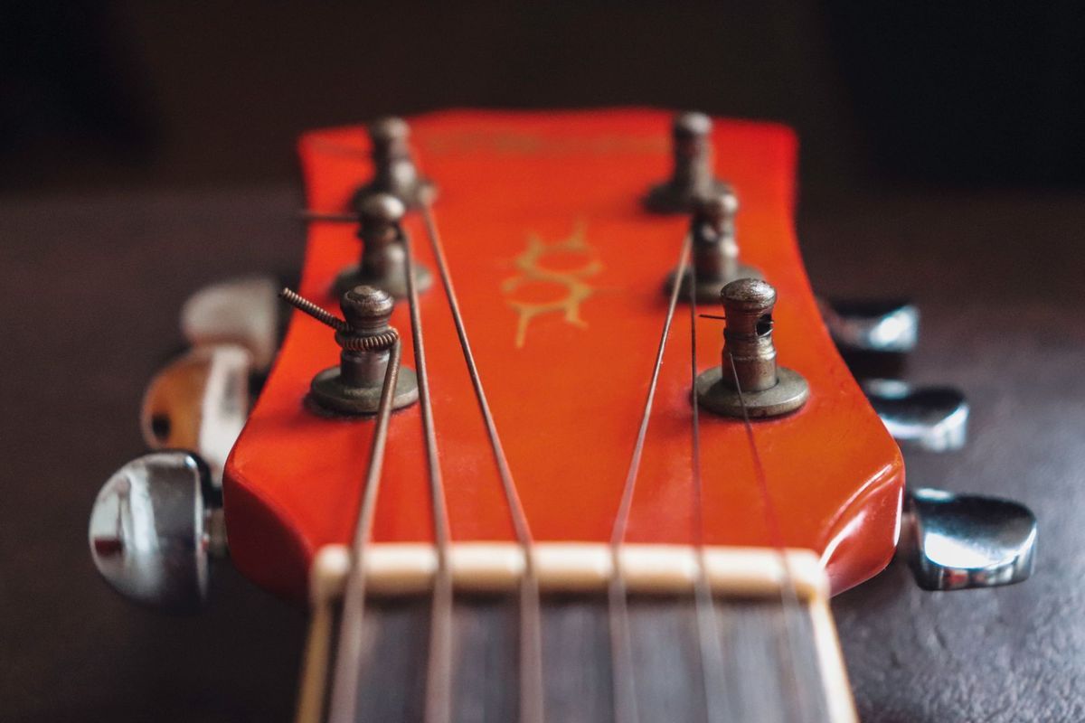 Red guitar headstock with strings and tuning pegs